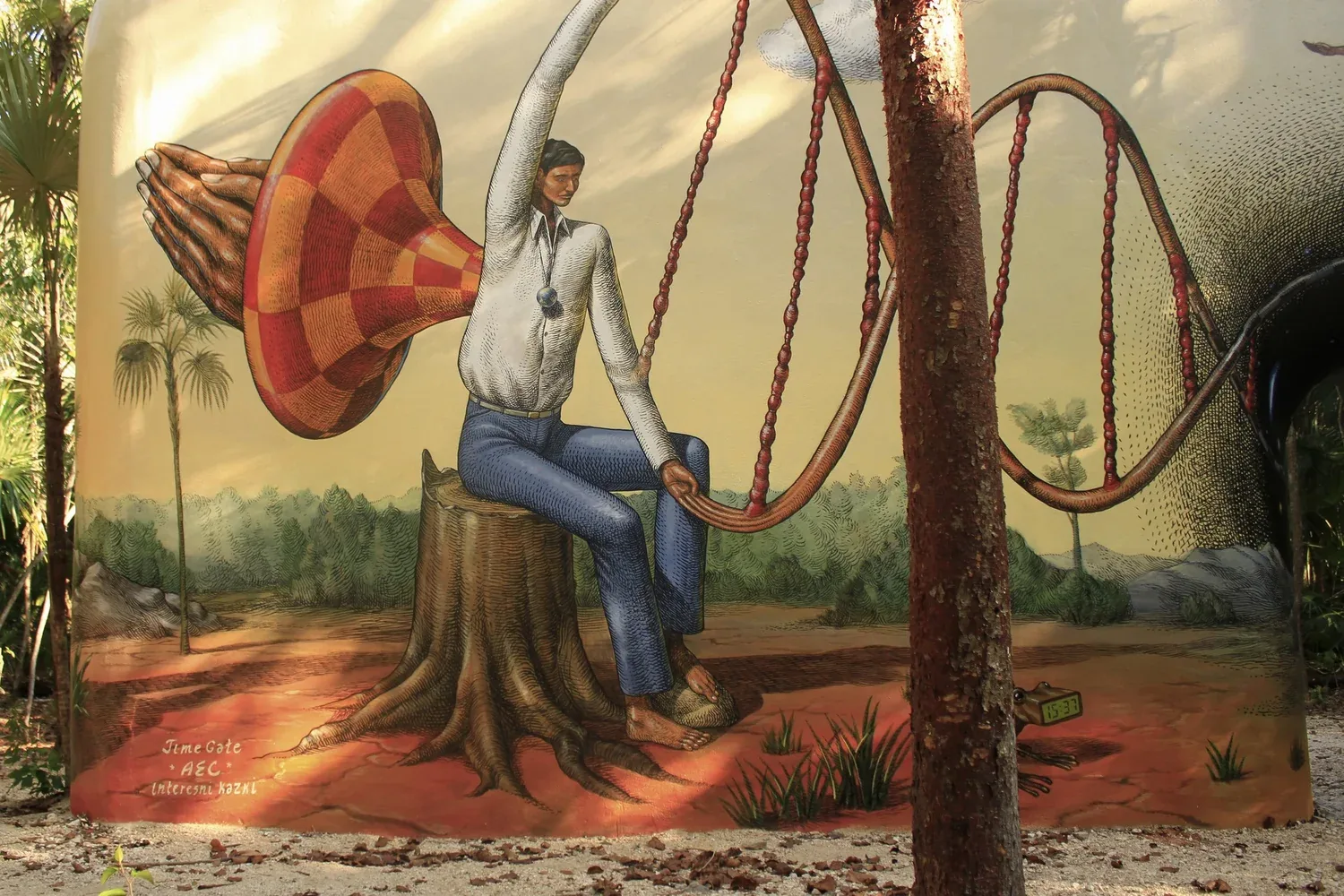 Large jungle mural of a seated man holding chains that curve across a pale sky at Holistika Art Walk in Tulum, Mexico.