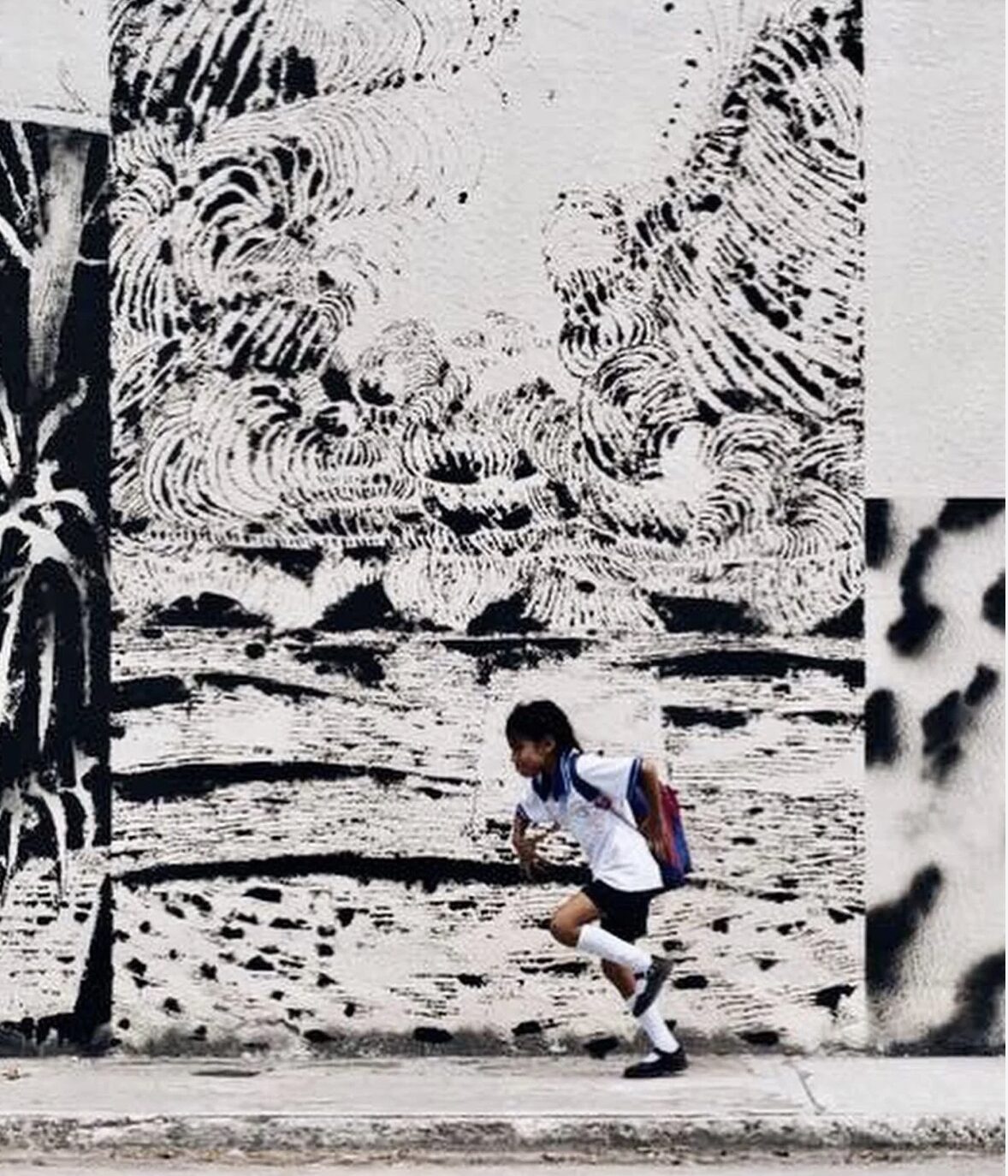 Artist finishing a large mural on an exterior wall in Tulum during a Tulum Art Club production day.